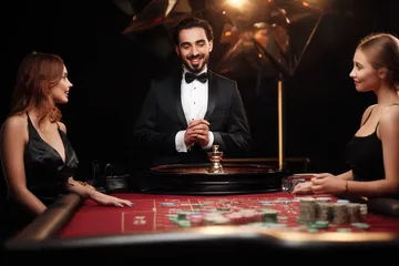 A professional dealer in a tuxedo greeting players at the roulette table, symbolizing the authentic live casino feel at A71.