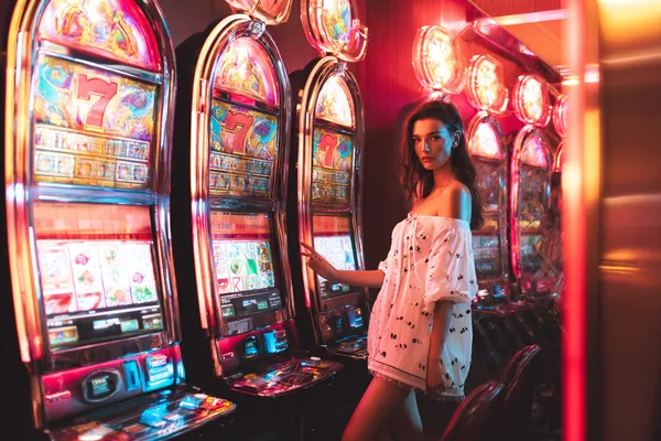 A stylish woman beside vibrant slot machines displaying glowing sevens, showcasing the variety of top slots at A71.