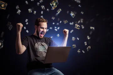 A man celebrating a winning moment on his laptop while gaming symbols float around him, capturing the excitement of A71 games.